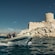 Visitantes en trajes de neopreno viajando en un bote zodiac frente a un fuerte en un acantilado